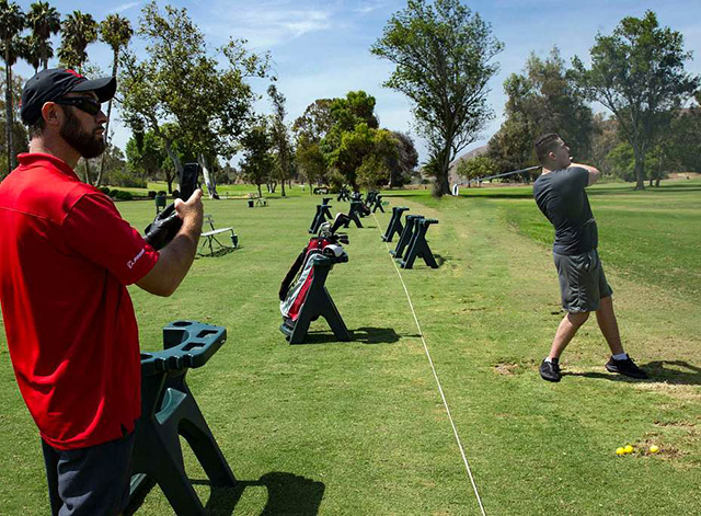 golf coach filming a player